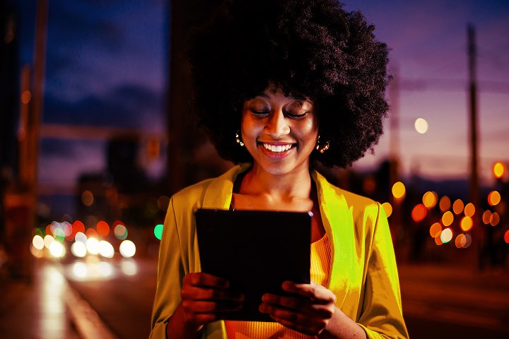 mulher sorrindo usando tablet à noite pagando GNRE em segundos com automação nacional e equipe livre de planilhas e retrabalho